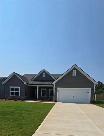 Single-story residence featuring grey siding, dark shingle roofing, and a prominent two-car garage
