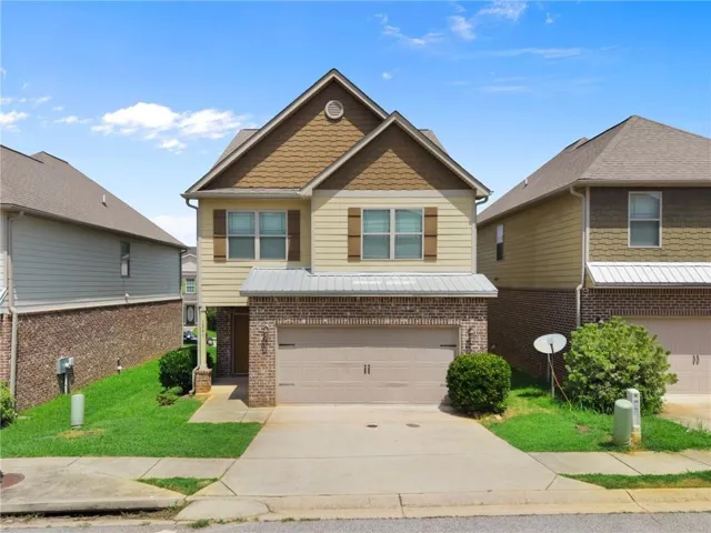 Two-story residence featuring brick and siding facade, an attached garage, and a covered entry