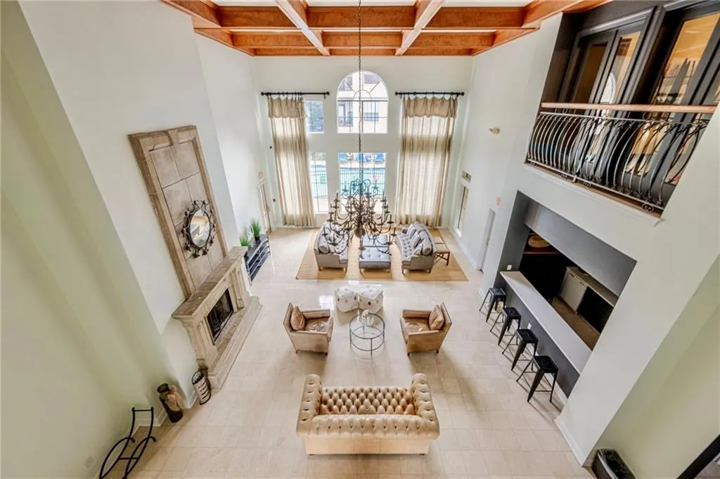 Clubhouse room with a fireplace, a towering ceiling, beamed ceiling, coffered ceiling, and a chandelier