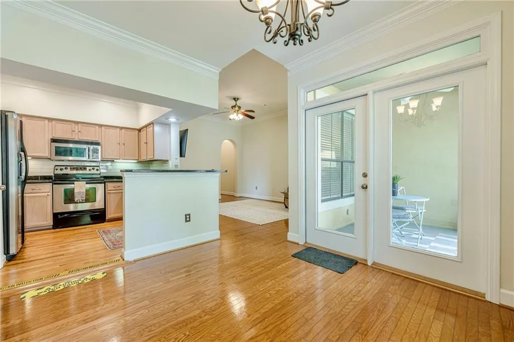 Kitchen featuring a chandelier, ornamental molding, stainless steel appliances, arched walkways, and decorative backsplash