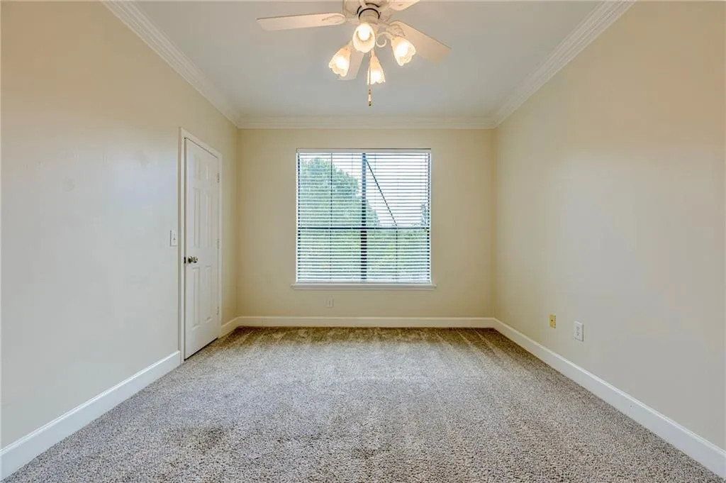 Spare room with carpet, ornamental molding, and ceiling fan
