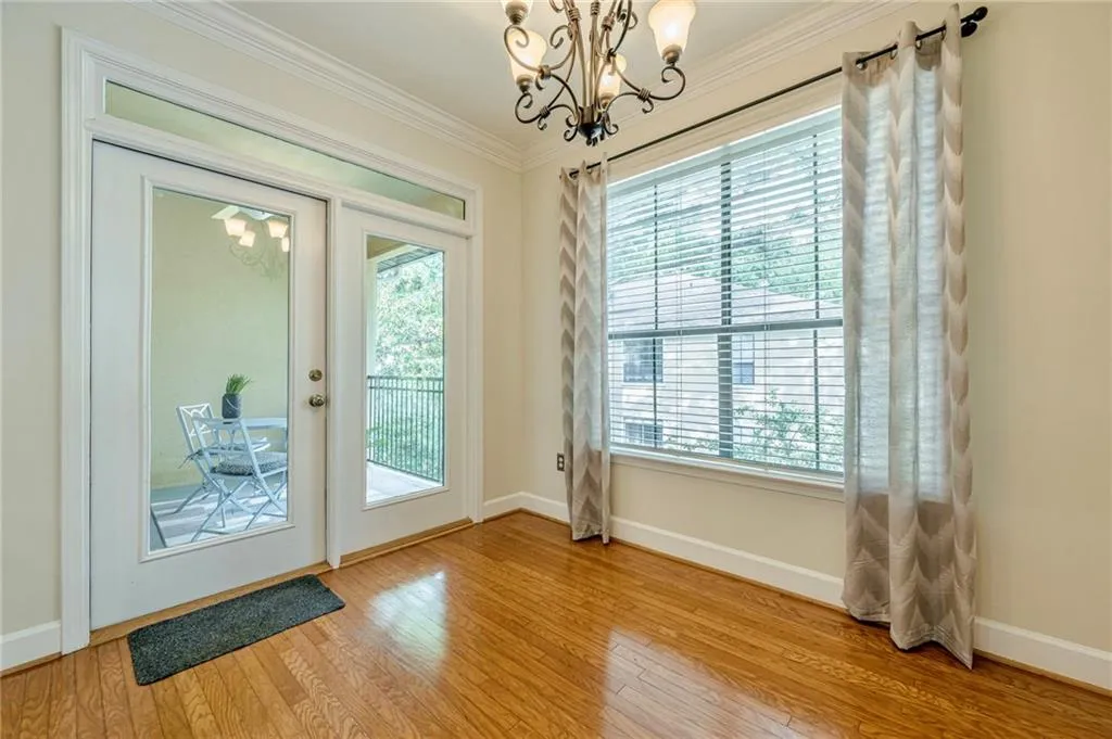 Doorway to outside with a chandelier, wood finished floors, and ornamental molding