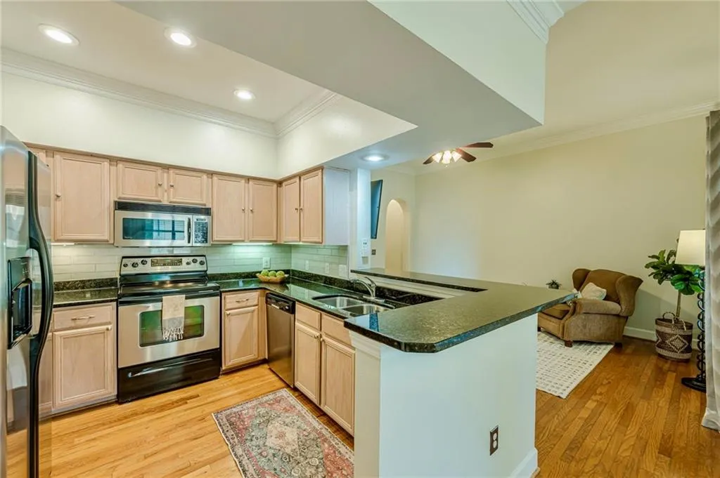 Kitchen featuring crown molding, stainless steel appliances, a peninsula, light wood-style flooring, and backsplash