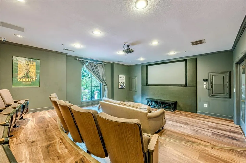Cinema room featuring crown molding, light wood finished floors, recessed lighting, and a textured ceiling