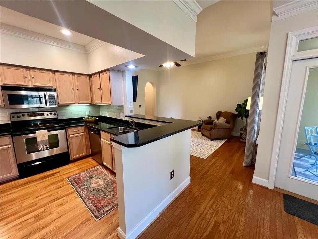 Kitchen featuring crown molding, stainless steel appliances, backsplash, a peninsula, and open floor plan