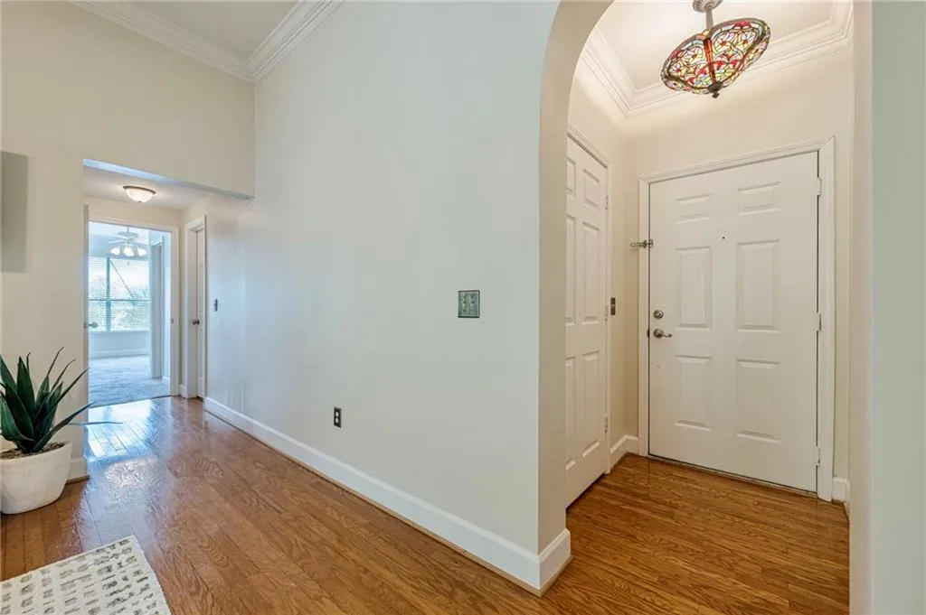 Foyer with ornamental molding, dark wood-style flooring, and arched walkways