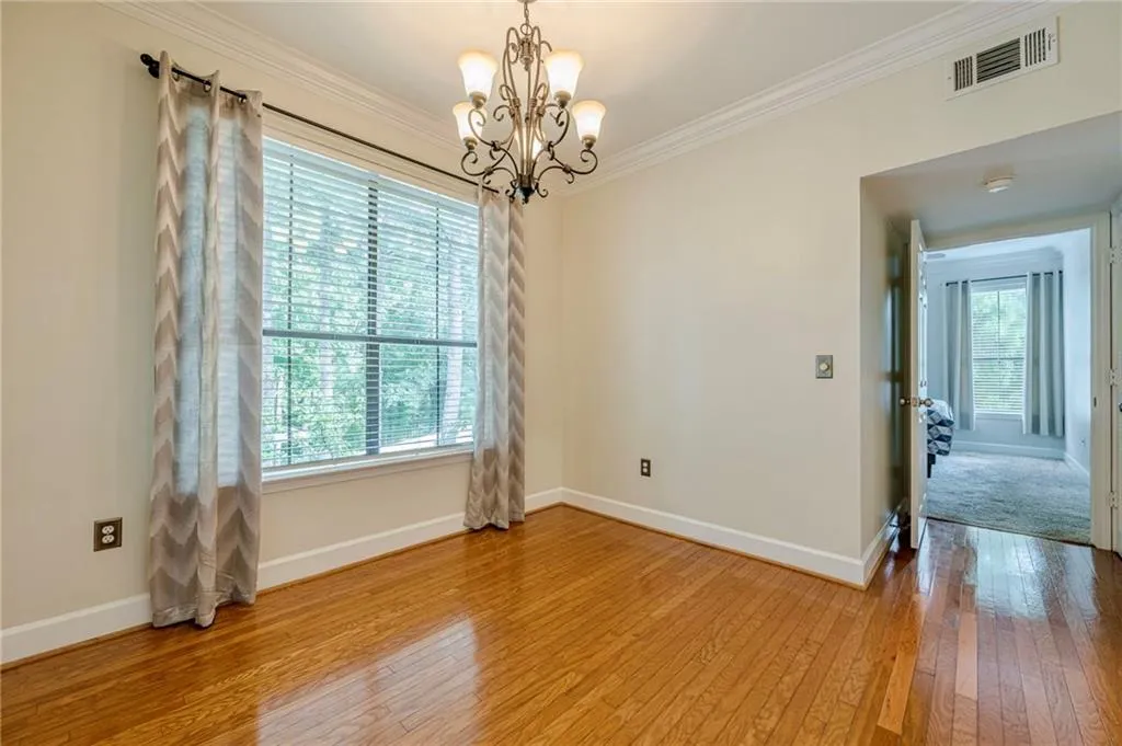 Unfurnished room featuring light wood finished floors, ornamental molding, and a chandelier