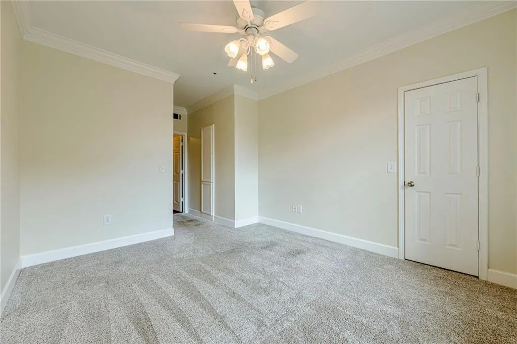 Secondary bedroom featuring ornamental molding, light colored carpet, and a ceiling fan