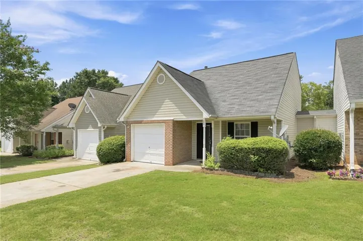 Exterior featuring a single-car garage, brick accents, light-toned siding, and a gabled roofline