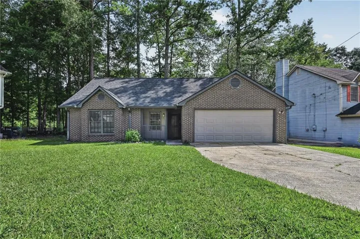Brick exterior, attached two-car garage, front lawn, concrete driveway, and mature trees