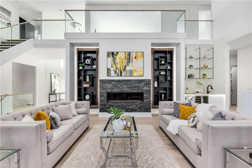 Living room with a towering ceiling, built in shelves, wood finished floors, a glass covered fireplace, and wine cooler