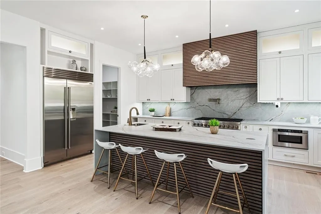 Kitchen with light stone countertops, white cabinetry, decorative light fixtures, stainless steel appliances, and extractor fan