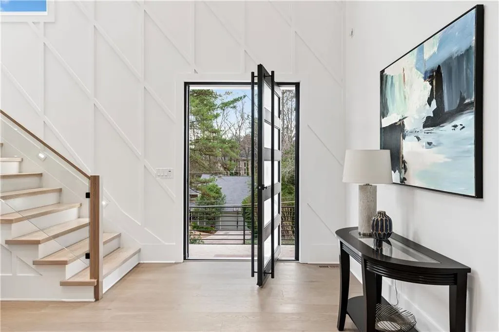 Foyer entrance with light wood-type flooring, stairway, and a decorative wall