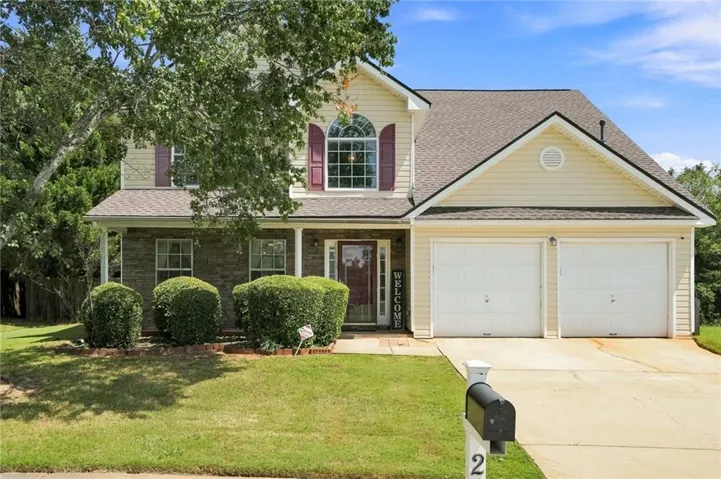Two-story residence featuring a covered front porch, stone and siding exterior, two-car garage, and an arched window