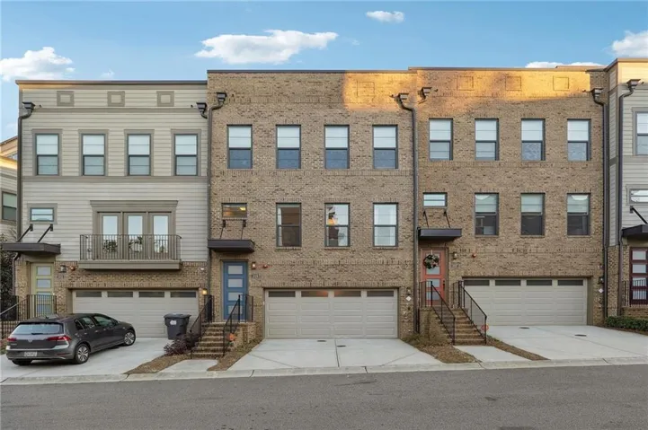 Brick and siding exterior with multiple garage bays, individual driveways, and covered entryways