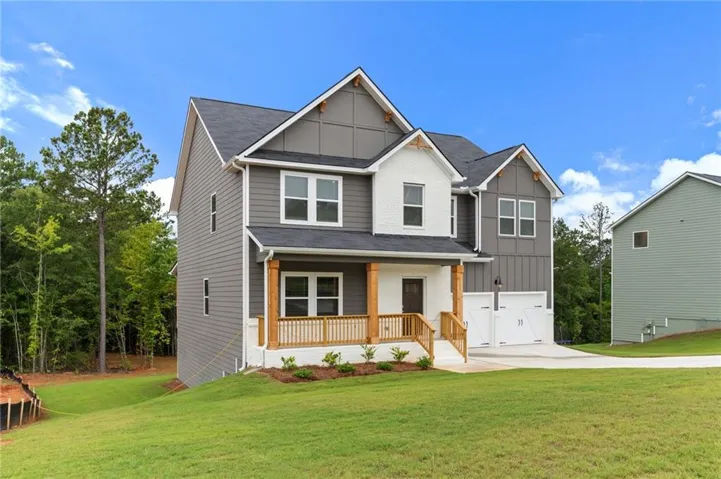 Modern two-story residence featuring a welcoming front-load garage, composite decking with wood-finish railings, multiple window openings with gray trim, and a sloped roof with architectural gabling