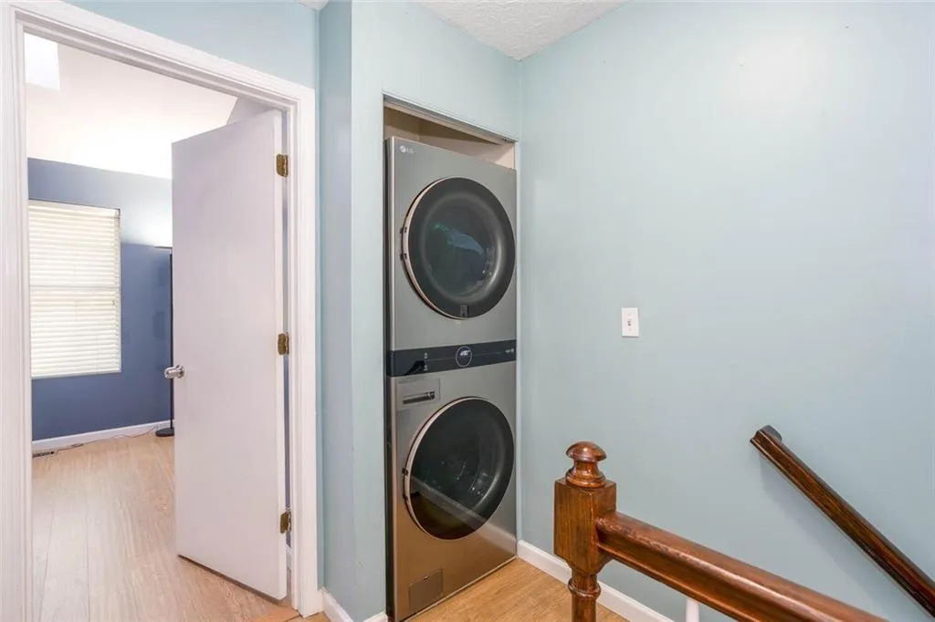 Washroom featuring light hardwood / wood-style flooring and stacked washer / dryer