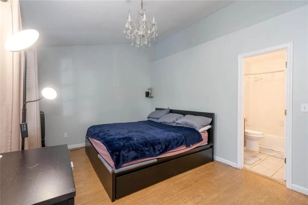 Bedroom featuring light hardwood / wood-style flooring, ensuite bath, and a chandelier