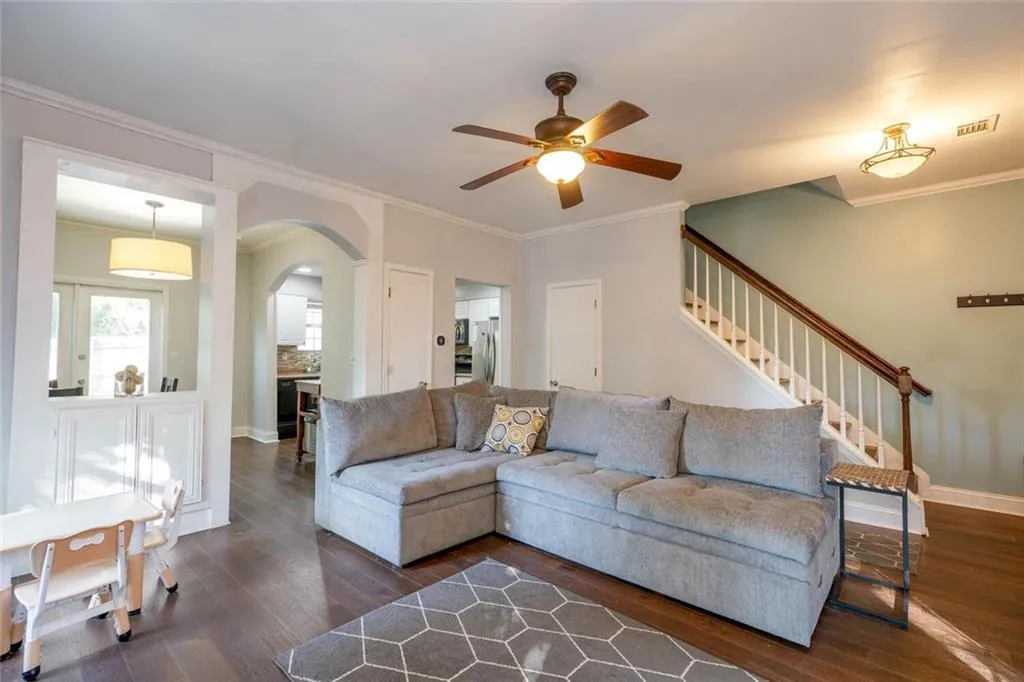 Living room with ceiling fan, dark hardwood / wood-style floors, and ornamental molding