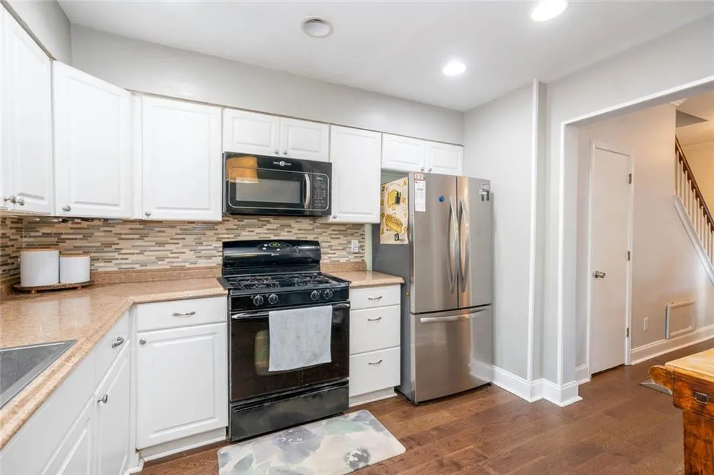 Kitchen featuring white cabinets, backsplash, dark hardwood / wood-style floors, and black appliances