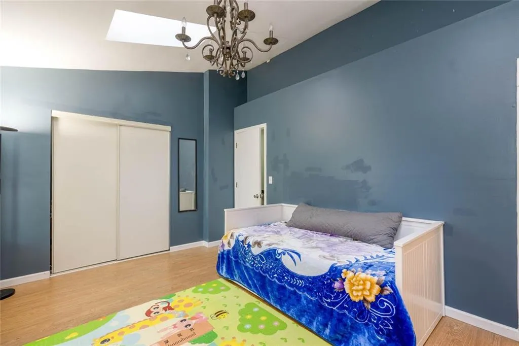 Bedroom with a notable chandelier, wood-type flooring, lofted ceiling, and a closet