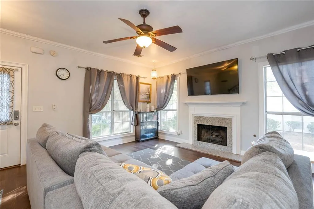 Living room with a premium fireplace, dark hardwood / wood-style floors, ceiling fan, and crown molding