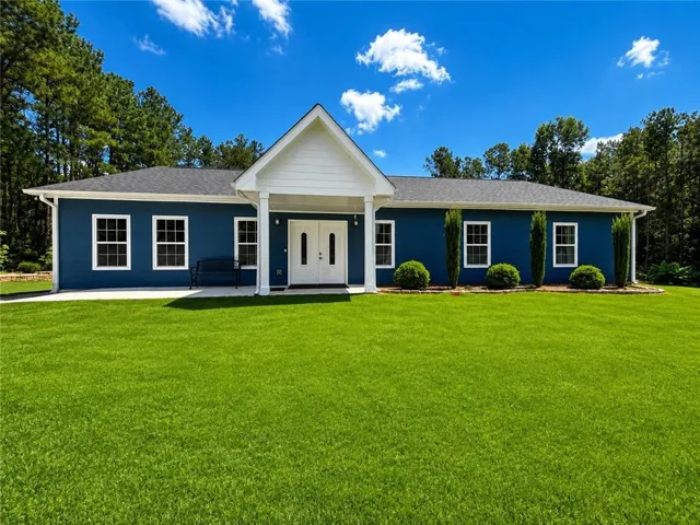 Ranch-style residence featuring a prominent gabled entry, white double-entry doors, and a dark shingle roof