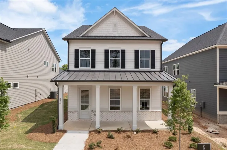 Two-story residence featuring light-colored siding with a contrasting dark metal roof over the front porch