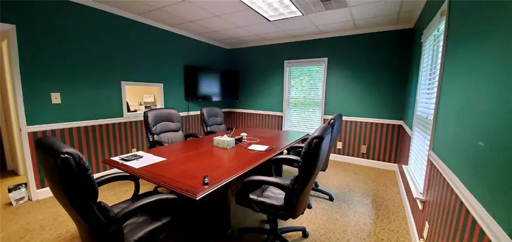 Conference room featuring a multi-pane window with blinds, wood-finish flooring, and a pass-through opening