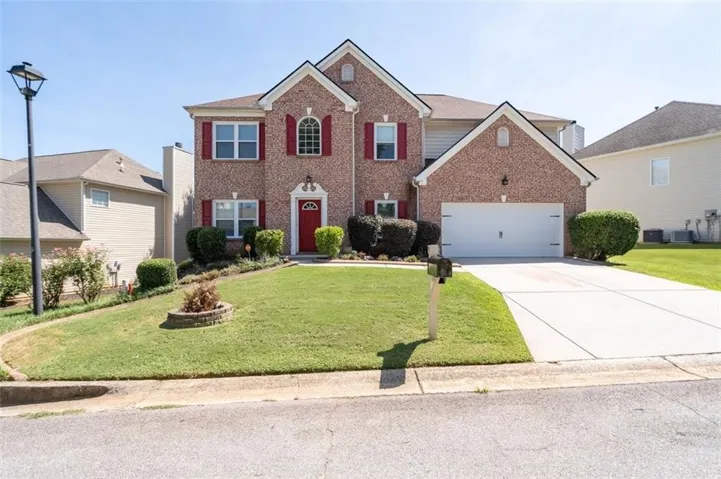 Brick facade with red accent shutters and a red entry door