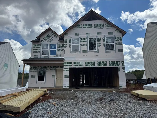 Two-story home under construction featuring a gable roof, covered entry, multiple windows, and an integrated garage space