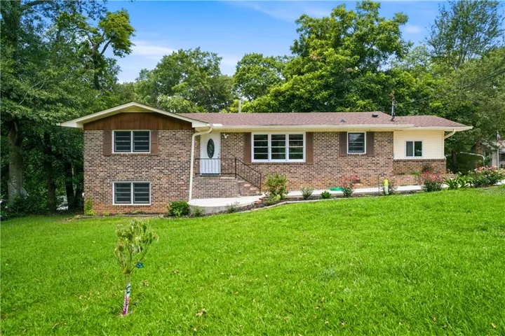 Brick split-level home set on expansive manicured lawn with mature tree canopy