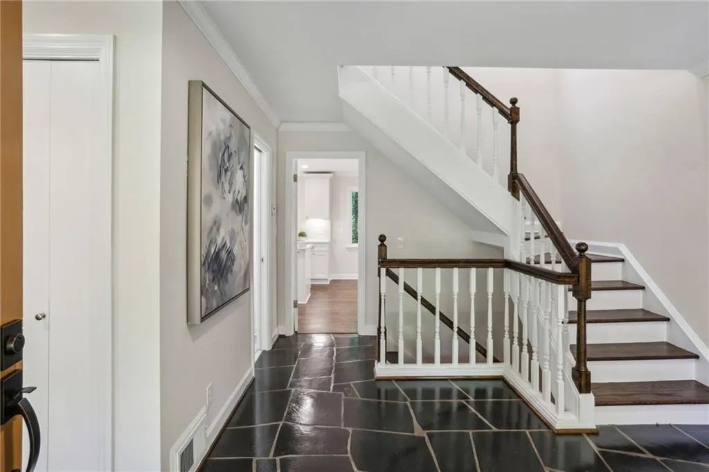 Foyer with polished bluestone slate flooring showing an abundance of light and oak staircase leading both up and down.