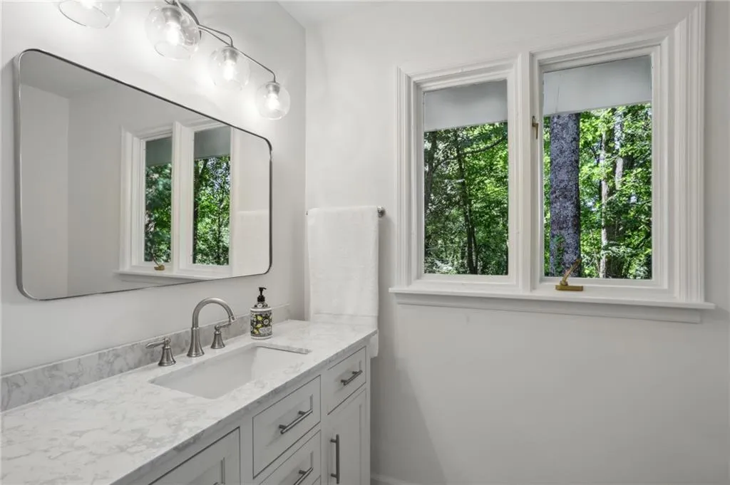 View of hall bathroom with brushed nickel fixtures and updated lighting and mirror