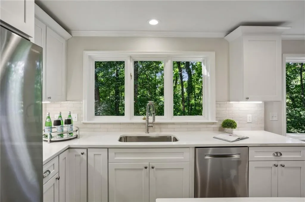 Kitchen featuring plenty of natural light, stainless steel appliances, white cabinets, and sink