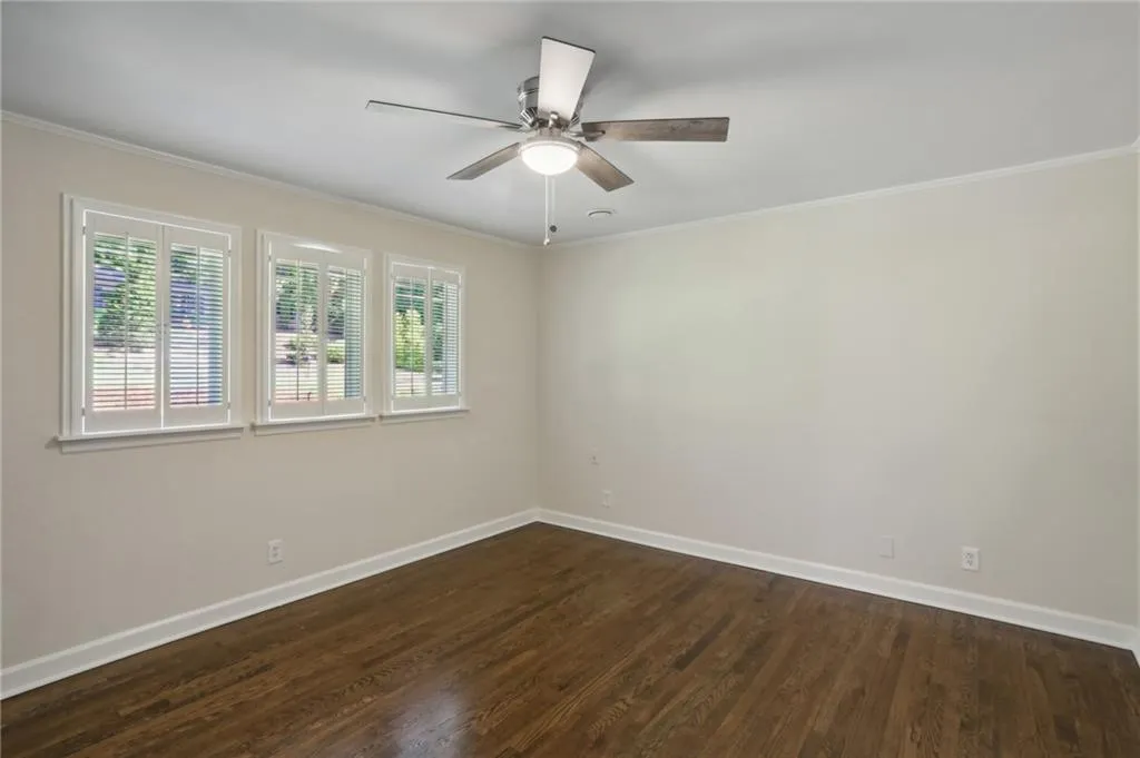 Sizable bedroom facing front of home with ceiling fan, built in closet, plantation shutter and hardwoods.