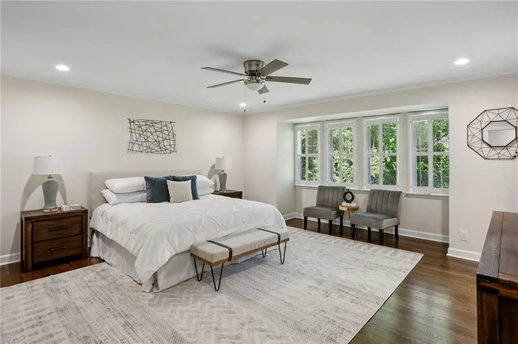 Oversized primary bedroom with ornamental molding, ceiling fan, updated lighting and hardwood floors