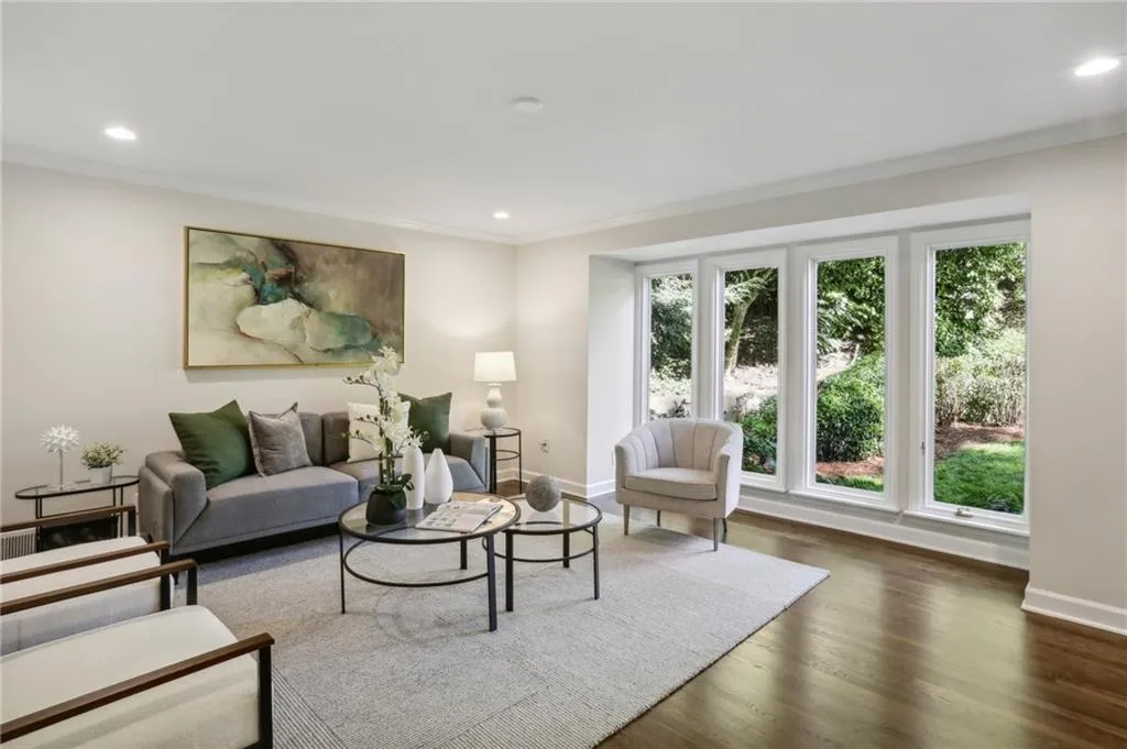 Corner view of living room with floor to ceiling windows overlooking the lush front yard
