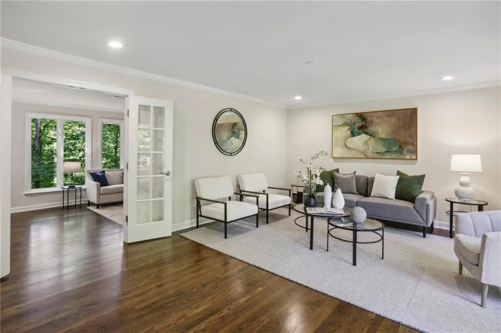 Living room with ornamental molding, gleaming hardwoods and French doors leading to family room