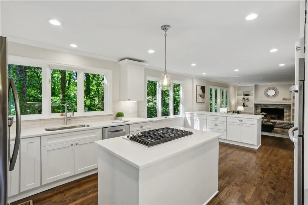 Kitchen with pendant light fixtures, white oak flooring, sink, and view of the woodburning fireplace