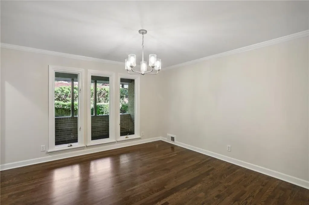Corner view of spacious Dining Room showing crown molding, casement windows, new lighting and refinished oak floors.