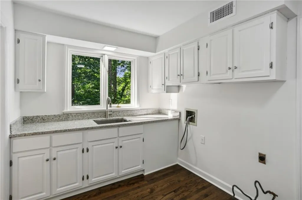 Laundry area featuring granite workspace and stainless sink.  Hookups for both washer and dryer are ready for your new appliances.