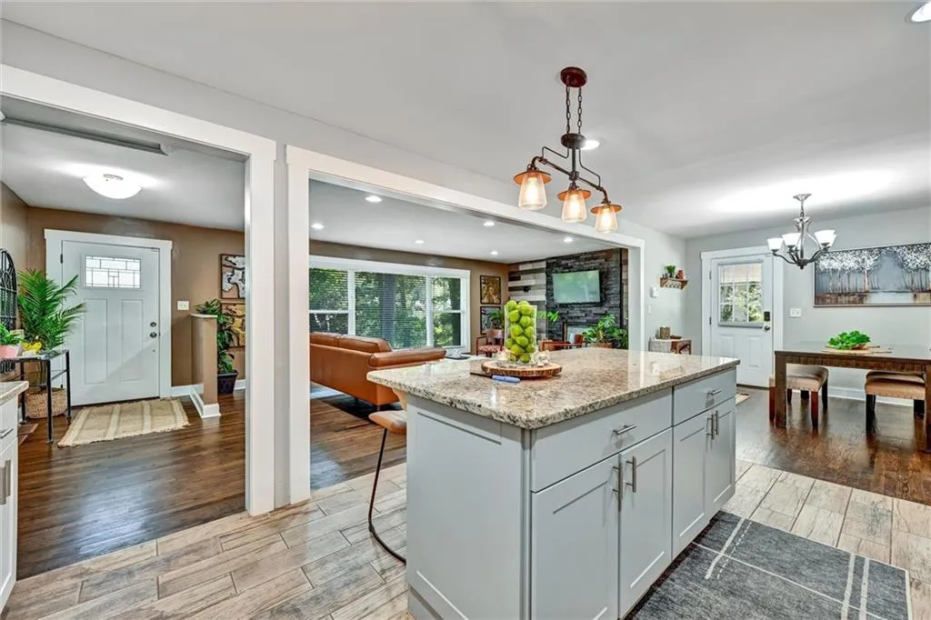 Kitchen featuring a breakfast bar, a center island, hanging light fixtures, light stone countertops, and light wood-style floors