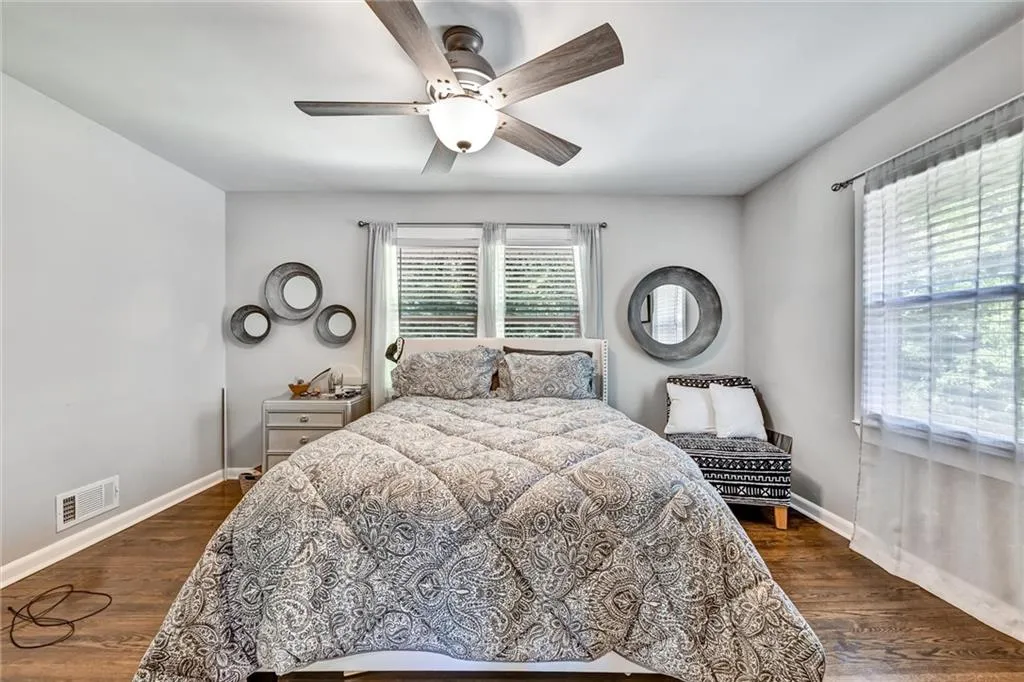 Bedroom with a ceiling fan, baseboards, visible vents, and dark wood-type flooring