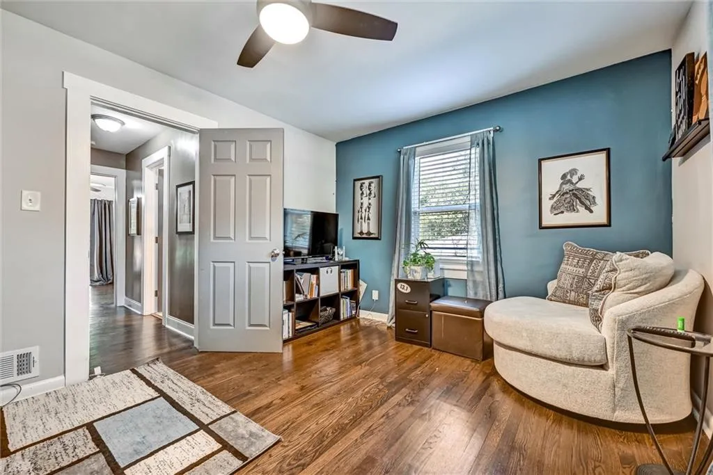 Living area with a ceiling fan, wood finished floors, visible vents, and baseboards