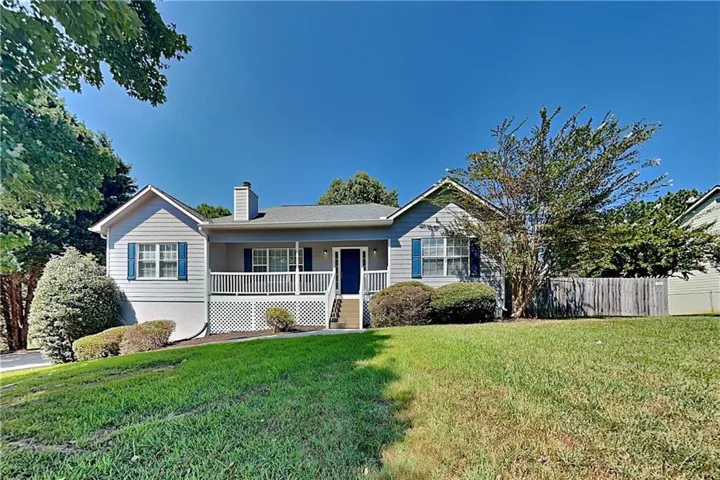 Single-story residence featuring light gray siding with blue window shutters, a covered front porch with white railings, and a prominent chimney