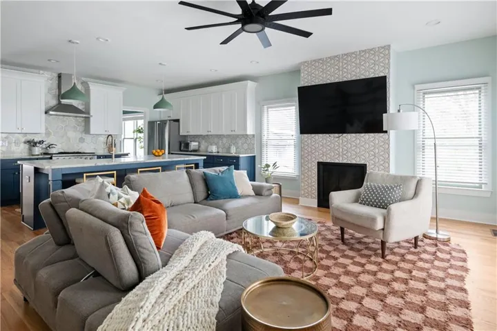 Living room featuring light wood finished floors, a ceiling fan, a fireplace, and recessed lighting