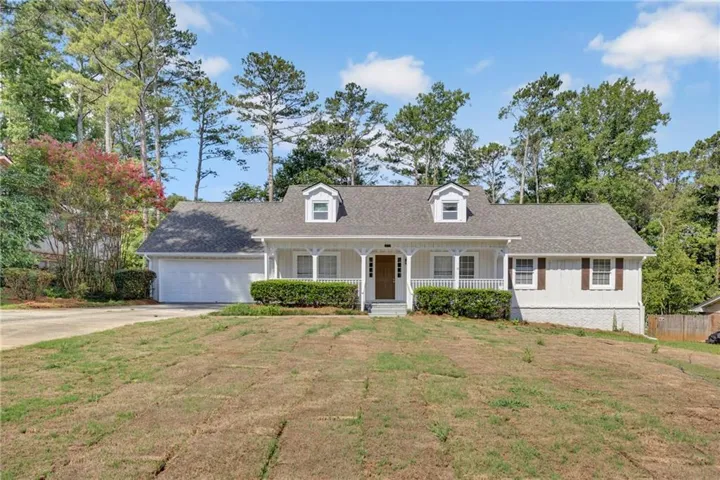 Ranch-style residence featuring a covered front porch with white columns, dormer windows, and a two-car garage