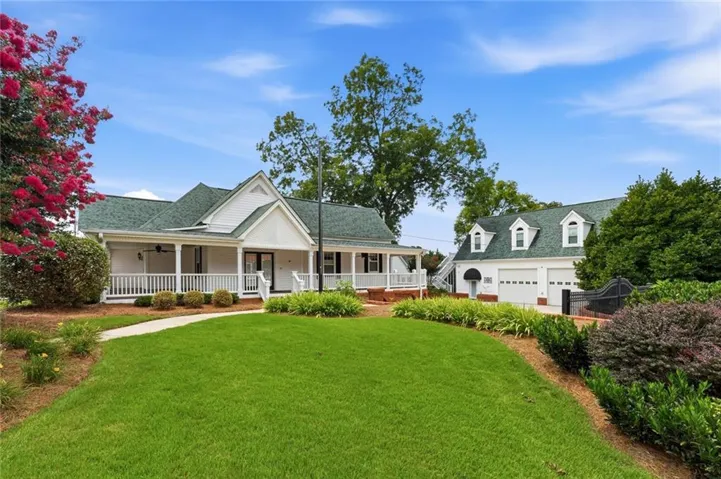 White-sided main residence featuring a covered front porch with white railings and a dark green shingled roof