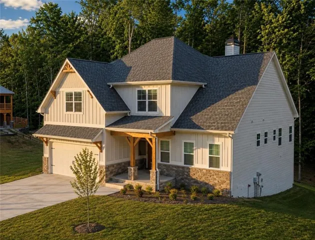 Craftsman-style exterior with board and batten siding, stone veneer accents, multi-pane windows, covered front porch with exposed timber framing, and an attached two-car garage